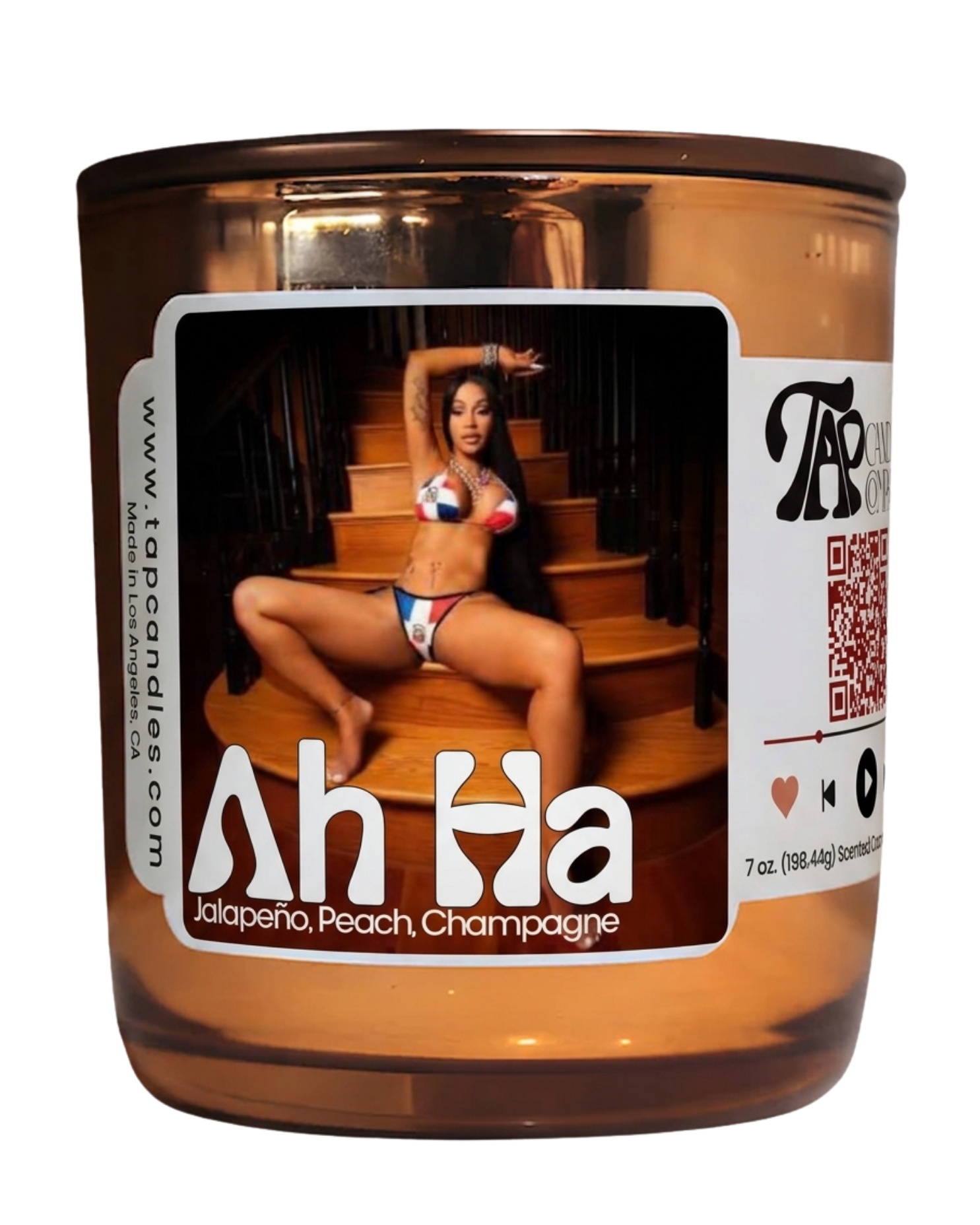 A 7 oz scented candle in a reflective amber glass jar with a dark brown lid. The front label features a photo of a woman sitting on wooden stairs, with the scent name 'Ah Ha' and notes 'Jalapeño, Peach, Champagne' printed below